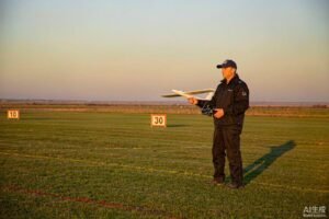 Beginner pilot holding a foam RC trainer airplane and transmitter on a grass field
